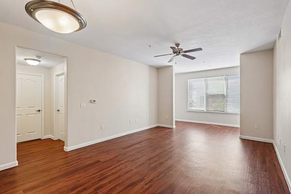A room with a ceiling fan and wooden floors.