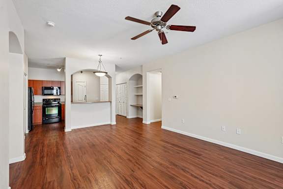 A room with a ceiling fan and wooden floors.