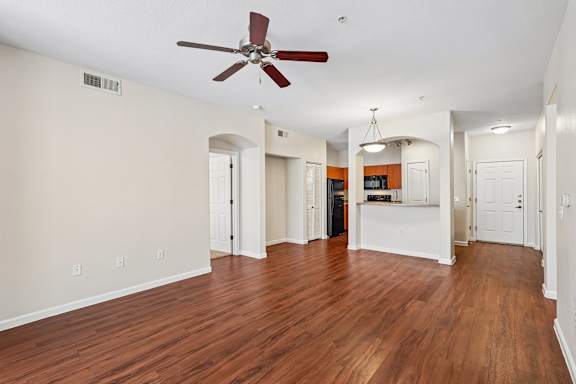 A room with a ceiling fan and wooden floors.