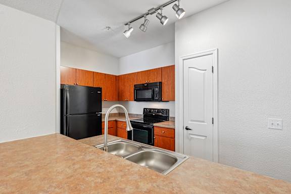A kitchen with black appliances and wooden cabinets.