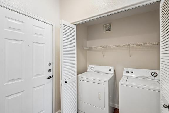 A white door is open to a laundry room with a washer and dryer.