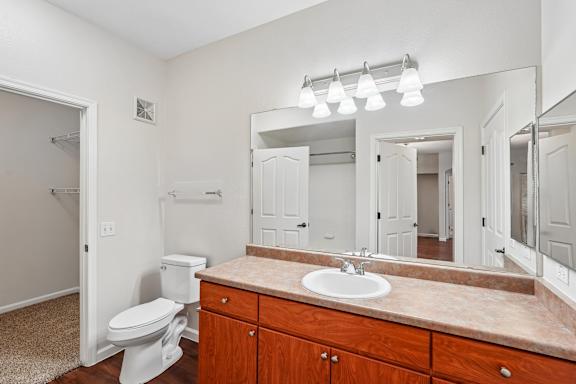 A bathroom with a toilet, sink, and mirror.