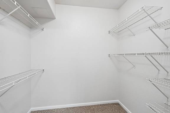 Empty walk-in closet with white shelving.