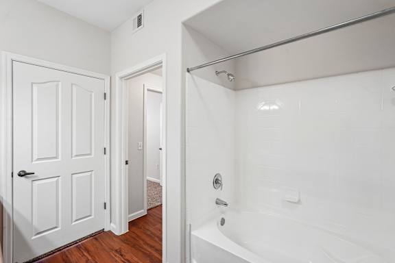 A white bathroom with a tub and a door.