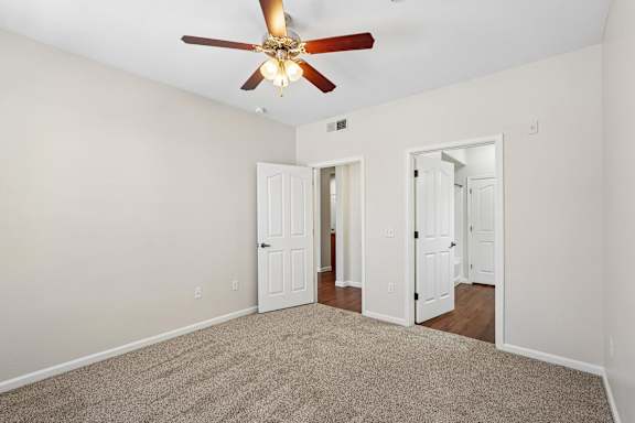 A room with a ceiling fan and carpeted floor.