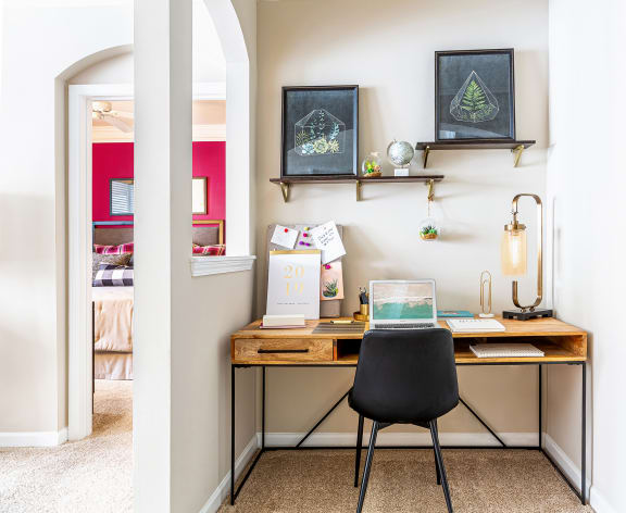 a home office with a wooden desk and a black chair