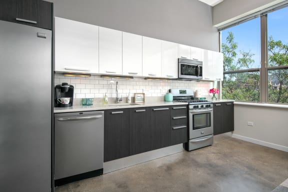 a kitchen with white cabinets and stainless steel appliances and a large window