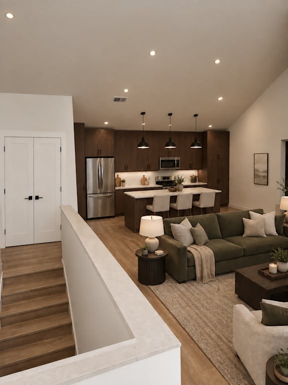 A modern kitchen with a refrigerator, microwave, and oven, with a dining area featuring a couch, chairs, and a coffee table.