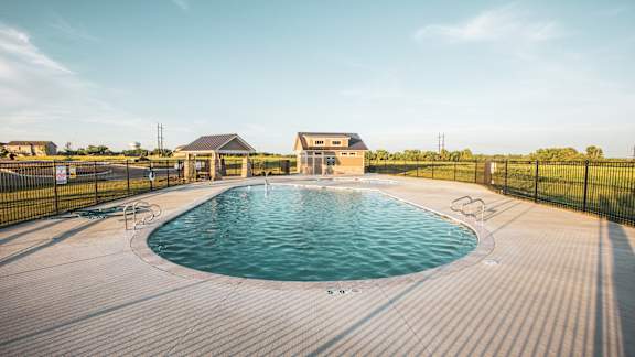 A large outdoor swimming pool surrounded by a black fence.