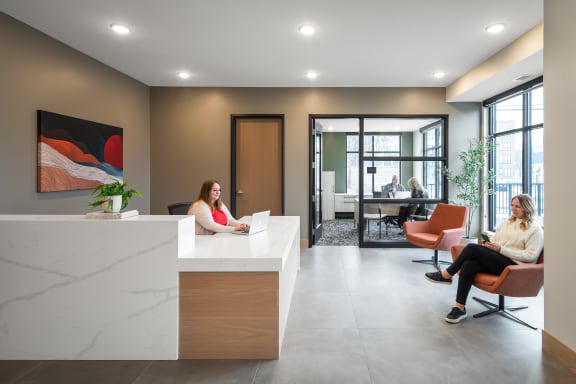 two women sitting in a lobby with their laptops