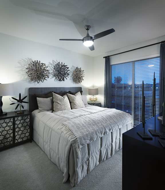 A bedroom with a bed, a ceiling fan, and a window with blinds.
