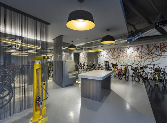 A yellow hydraulic lift in a room with bicycles on the wall.