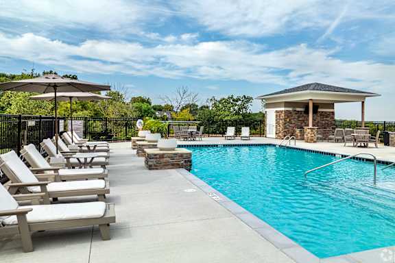 A pool with a gazebo and sun loungers.