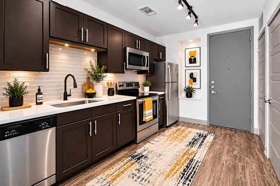 A modern kitchen with dark brown cabinets and a white backsplash.