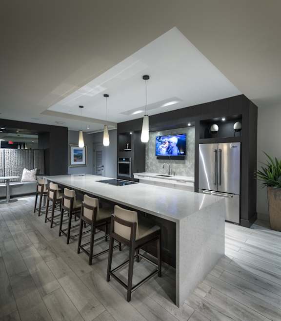 A modern kitchen with a long bar and stools.