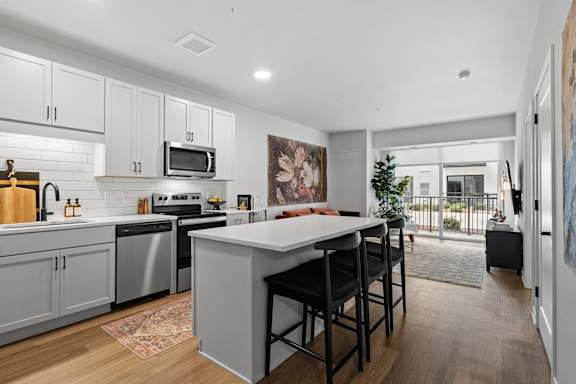 A kitchen with a white island and bar stools.