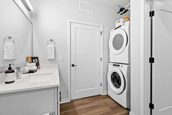A white bathroom with a washer and dryer in the corner.