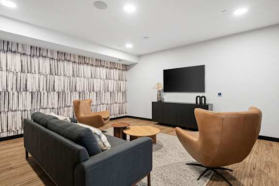 A living room with a grey couch, a brown chair, and a black television.