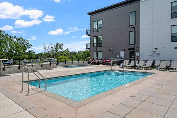 A swimming pool in front of a grey building.