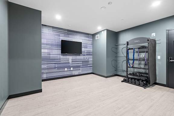 A room with a wooden floor and a television on the wall.