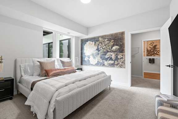 A bedroom with a large bed and a painting on the wall.