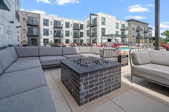 A modern outdoor seating area with a fire pit in the center.