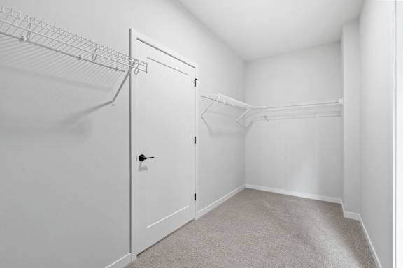 A white door is in a white room with a grey carpet.