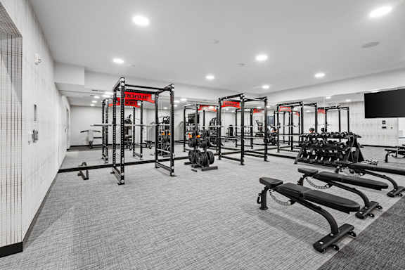 A gym with a variety of equipment including treadmills, weights, and exercise machines.