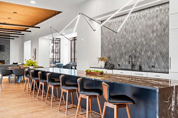 A modern kitchen with a long bar and chairs.