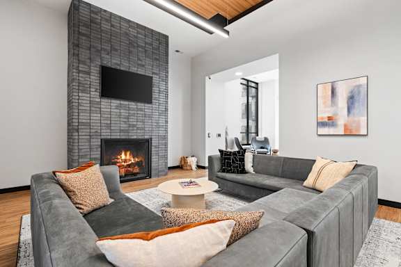 A modern living room with grey couches and a fireplace.