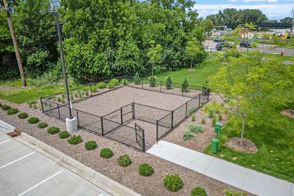 A playground with a fence and a green trash can.