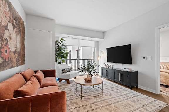 A living room with a brown sofa and a large painting on the wall.