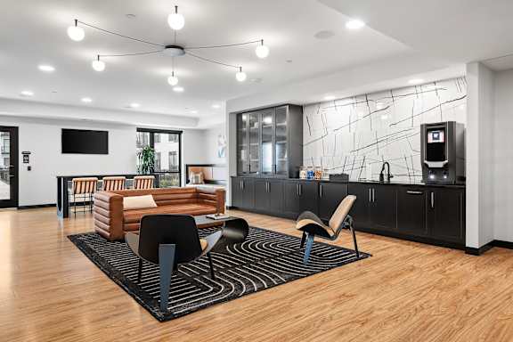 A modern living room with a wooden floor and a black and white rug.