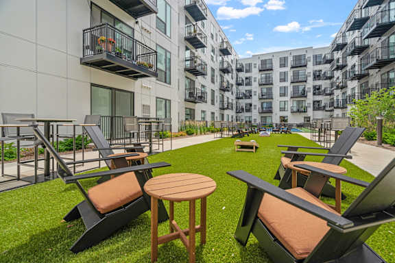A patio with chairs and tables is surrounded by apartment buildings.