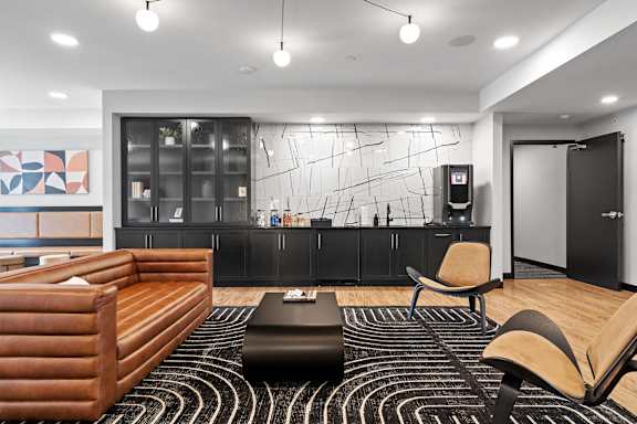 A modern living room with a wooden sofa and a black and white rug.