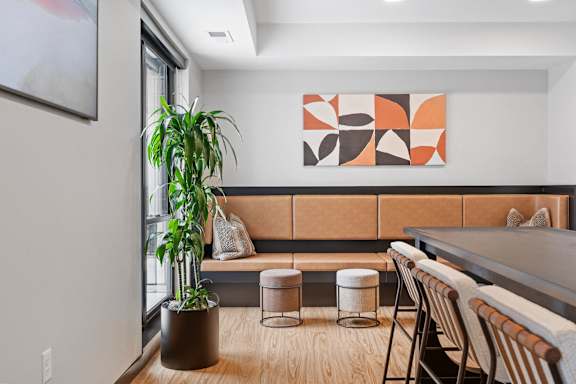 A room with a brown couch and a painting on the wall.