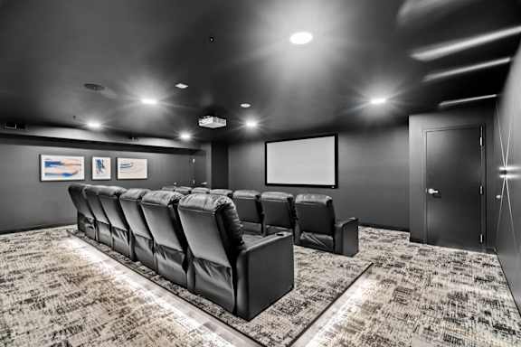 A black and white photo of a movie theater with a row of seats and a screen.