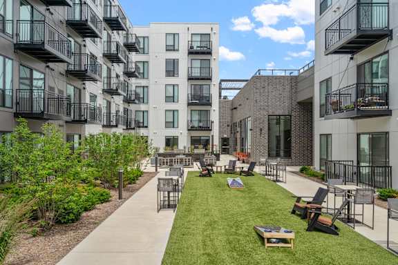 A sunny day at a modern apartment complex with a grassy courtyard and balconies.