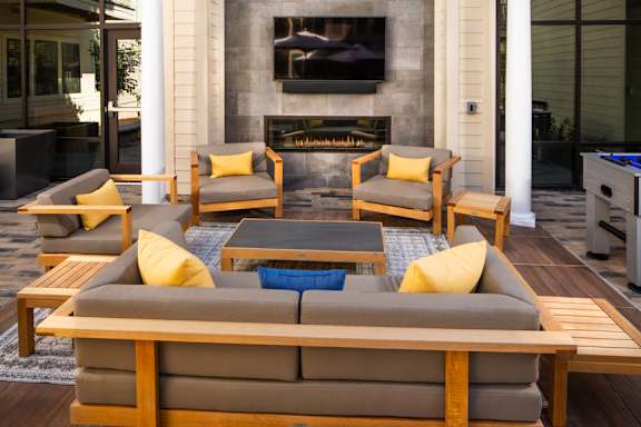 A modern outdoor seating area with a fireplace and a television.