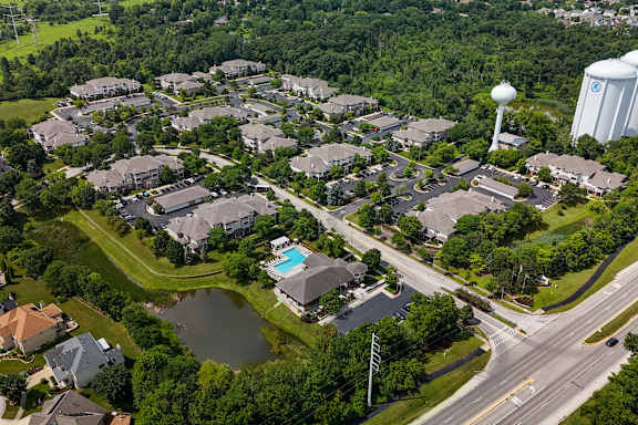 A bird's eye view of a residential area with houses, a pond, and a road.