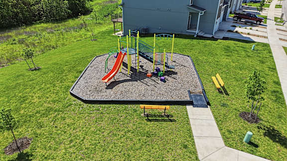 A playground with a slide, swings, and a bench.