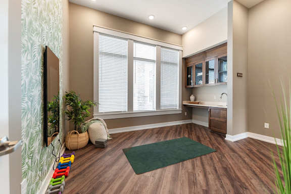 A room with a green rug and wooden floors.