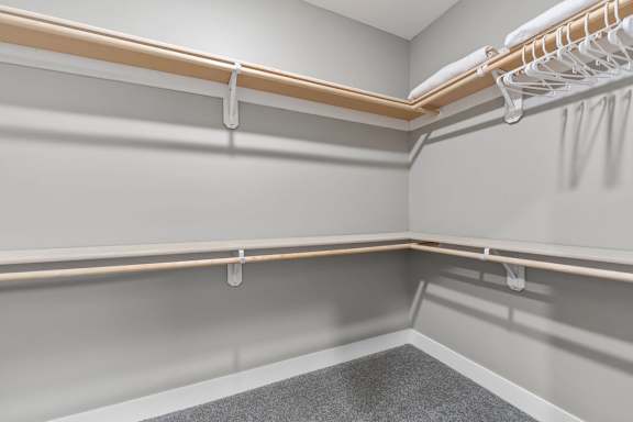A walk-in closet with white shelves and a grey carpet.