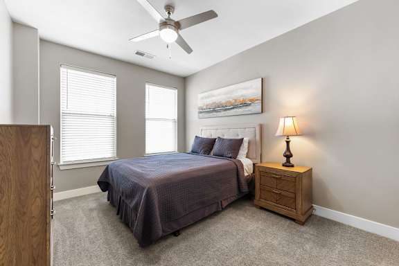A bedroom with a bed, nightstand, and a painting on the wall.