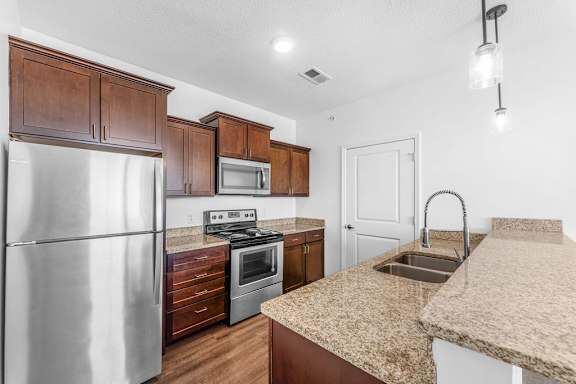 A kitchen with a stainless steel refrigerator, microwave, oven, and sink.