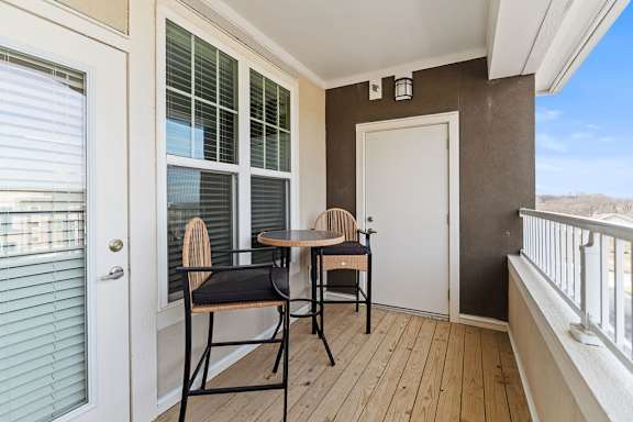 A balcony with a table and chairs.