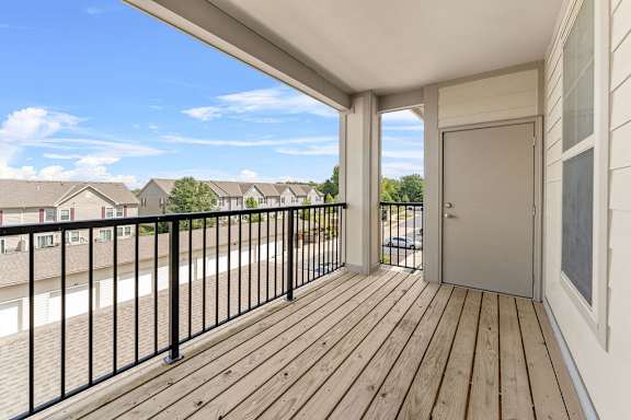 A balcony with a black railing and wooden floor.