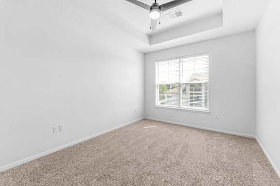 A room with a ceiling fan and a window with blinds.