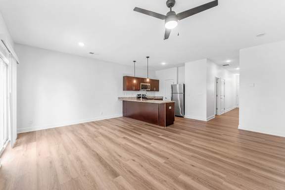A room with a ceiling fan and wooden flooring.
