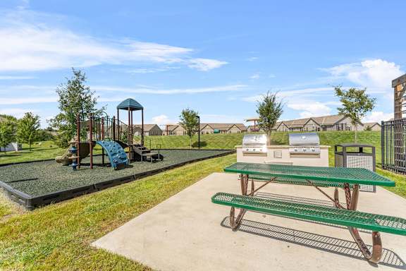 A playground with a green picnic table and a blue swing set.